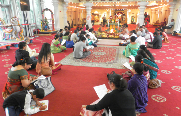Priests lead a sanctifying puja as the faithful follow along.