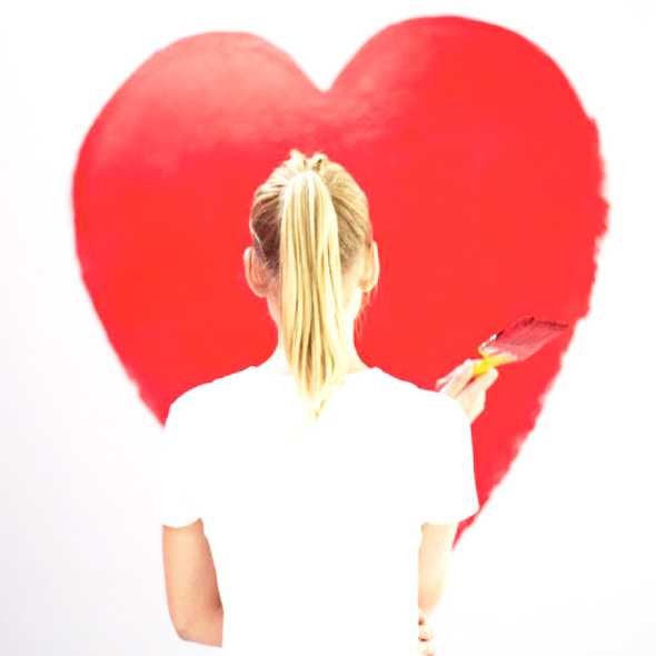 young woman painting a red heart on the wall
