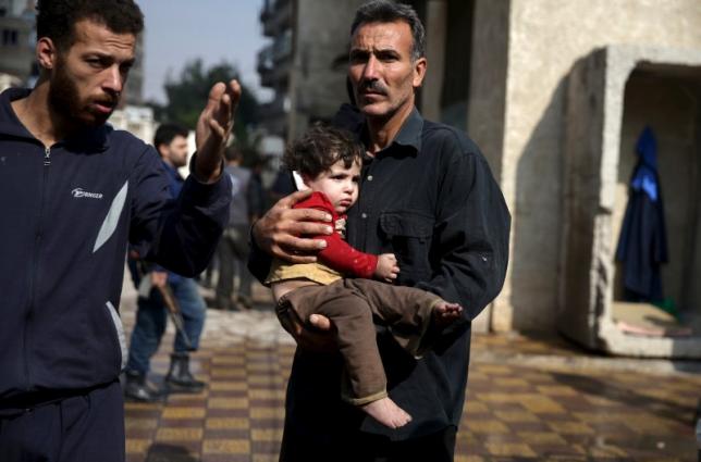 A man carries an injured child as another man gestures at a site hit by missiles fired by Syrian government forces on a busy marketplace in the Douma neighborhood of Damascus, Syria