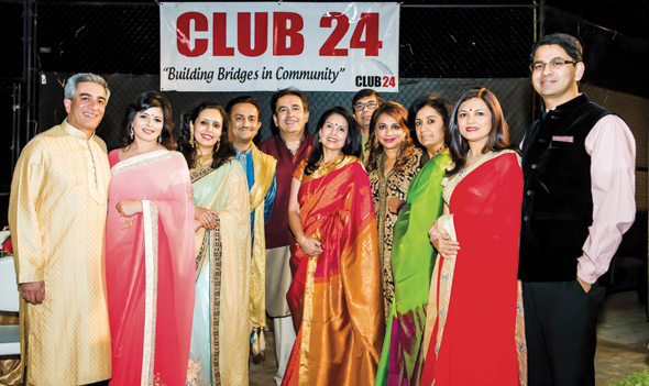 A select group of Club 24 couples pose in front of the Club 24 banner.
