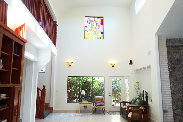 The new vaunted living room with a curved ceiling and stained glass windows reminiscent of Frank Lloyd Wright’s designs. The water wall is on the right.