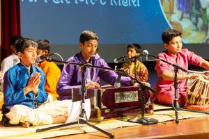 Young children singing kirtans and playing traditional musical instruments