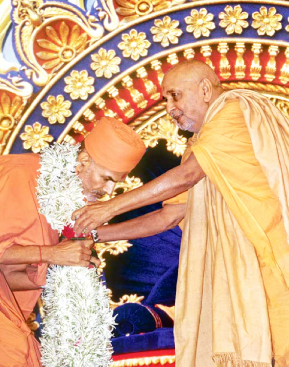 Mahant Swami receiving a garland from Pramukh Swami Maharaj