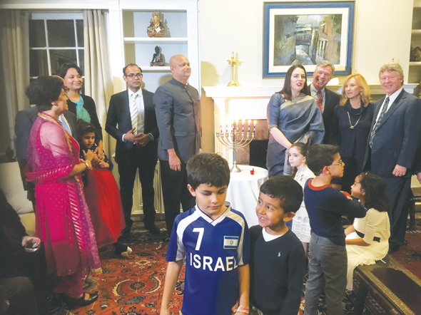 A highlight of the Hanukkah celebration at Consul General of India’s home included lighting of the Menorah (candelabra seen at the center) by CG’s children and other young guests in the foreground. Seen in the background are Marie Goradia (left), Aparna Ray, Asst. Consul General Surendra Adhana, CG Dr. Anupam Ray, CG’s wife Dr. Amit Goldberg Ray, representatives of the American Jewish Congress, Israeli Consulate, and Harris County Judge Ed Emmett.
