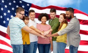 diversity, teamwork, race, ethnicity and people concept - international group of happy smiling men and women holding hands together over american flag background