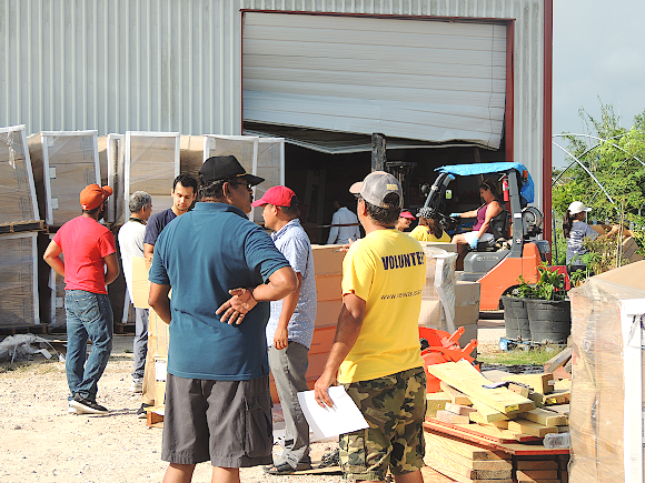 Sewa International’s Houston Chapter Coordinator Achalesh Amar (in yellow T-Shirt) supervising the distribution of construction materials to Harvey affected residents in Rosharon, TX.